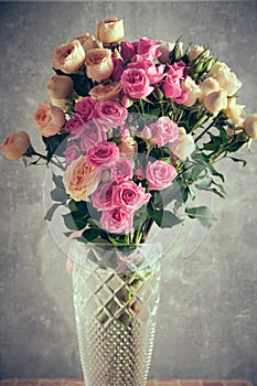 Bouquet of pink and white roses in vase on concrete background.