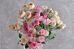 Bouquet of pink and white roses in vase on grey background.