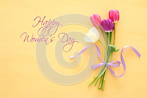 bouquet of pink and white tulips over pastel wooden background. Top view. International women day concept.