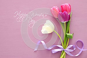 bouquet of pink and white tulips over pastel wooden background. Top view. International women day concept.