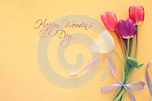 bouquet of pink and white tulips over pastel wooden background. Top view. International women day concept.