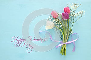 bouquet of pink and white tulips over pastel wooden background. Top view. International women day concept.