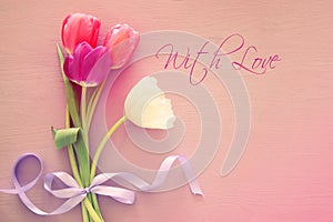 bouquet of pink and white tulips over pastel wooden background. Top view. International women day concept.