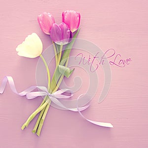 bouquet of pink and white tulips over pastel wooden background. Top view. International women day concept.