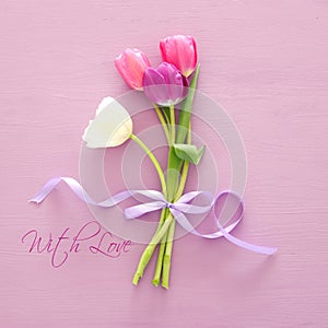 bouquet of pink and white tulips over pastel wooden background. Top view. International women day concept.