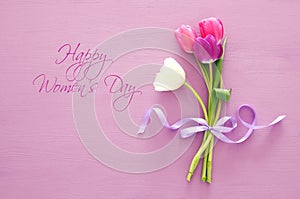 bouquet of pink and white tulips over pastel wooden background. Top view. International women day concept.