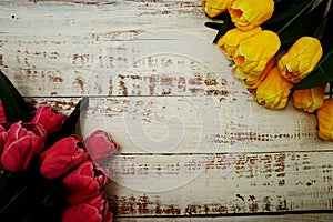 Bouquet of pink and yellow tulips on white wooden background