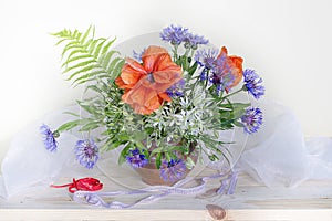 Bouquet with poppies, cornflowers, snowdrops in a vase on a white background