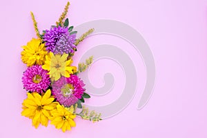 Bouquet of purple asters and yellow daisies on a pink paper background, mockup with copy space for text. Festive template, floral