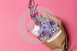 A bouquet of purple dried flowers in craft paper on a purple background. Top view. Flat lay mock up. Copy space