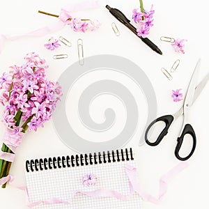 Bouquet of purple flowers, shabby tapes, clips, pen, scissors and notebook on white background. Flat lay, top view.