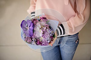 Bouquet of purple fresh flowers in the hands of girl in pink blouse.