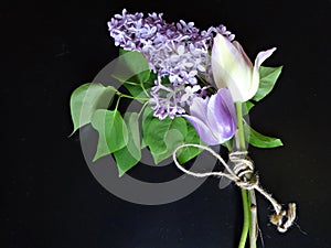 Bouquet of purple lilacs and tulips on a dark background