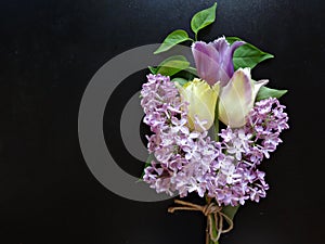 Bouquet of purple lilacs and tulips on a dark background