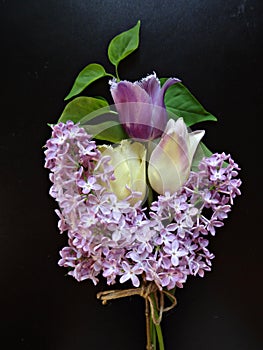 Bouquet of purple lilacs and tulips on a dark background