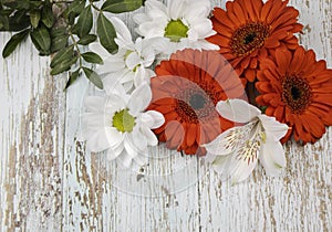 A bouquet of red gerberas, white lilies and daisies, isolated on a wood background.