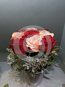 Bouquet of red and pink roses with green twigs on a gray background