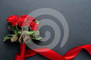 A bouquet of red roses with a beautiful ribbon on a black background, copyspase