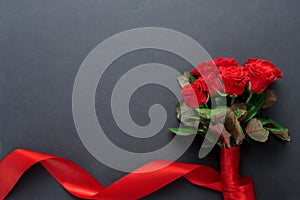 A bouquet of red roses with a beautiful ribbon on a black background, copyspase