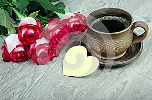 bouquet of red roses and a cup of coffee on a wooden table. top view