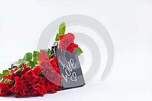 A bouquet of red roses and a letter with the text of love. Gift and flowers on a white background. The concept of lovers day and