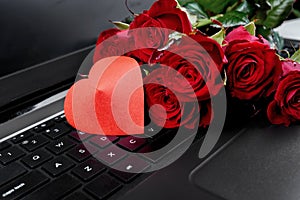 Bouquet of red roses and paper heart on keyboard of open laptop computer, copy space. Greeting card for Valentines Day, Womens Day