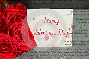 Bouquet of red roses and a sheet of white paper with a congratulation on Valentine`s day,
