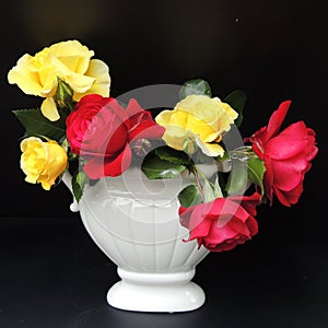 And a bouquet of red roses in a white vase on a black background