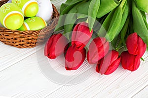 Bouquet red tulip flowers with easter eggs on old wooden table