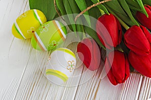 Bouquet red tulip flowers with easter eggs on old wooden table