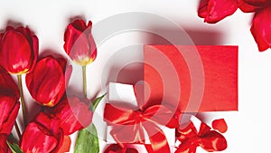 Bouquet of red tulips, envelope, gift box, on a white background. Valentine`s Day greeting card. Copy space. Top view