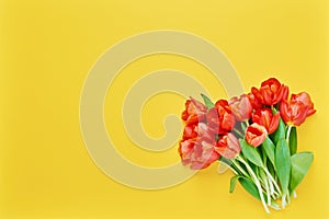 Bouquet of red tulips on a yellow background. Beautiful greeting card. Holidays concept. Copy space, top view