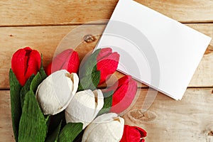 Bouquet of red and white craft paper tulips and white mockup blak on wooden background.