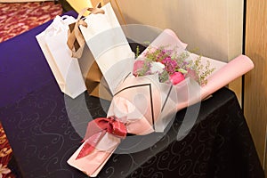 A bouquet of red white flowers and a couple of gift bags wrappings on a table photo