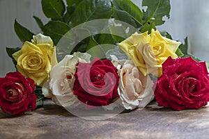 Bouquet of red, yellow and cream roses. On a wooden background, which stand on the windowsill. Window. Summer flowers