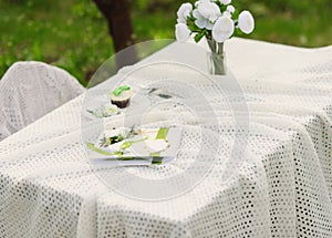 bouquet of roses and  cake on plate on the table in the garden