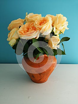 Bouquet of roses in a clay vase on a blue background