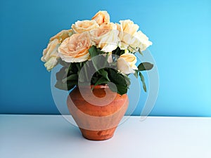 Bouquet of roses in a clay vase on a blue background