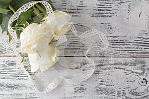 Bouquet of roses decorated with lace on white wooden background