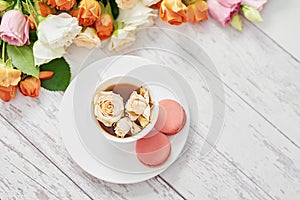 Bouquet of roses, eustomas and hydrangeas on table. Cup of tea or coffee and macaroons. Greeting card for mothers day. Cozy good