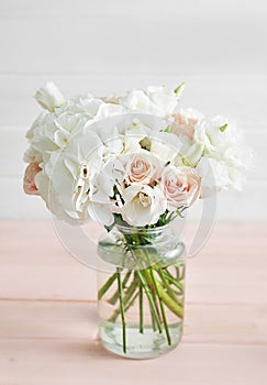 Bouquet of roses, eustomas and hydrangeas on table. Cup of tea and photo frame. Greeting card for mothers day. Cozy good morning.