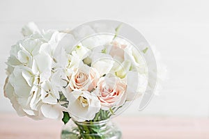 Bouquet of roses, eustomas and hydrangeas on table. Cup of tea and photo frame. Greeting card for mothers day. Cozy good morning.