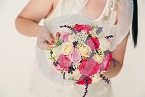 Bouquet of roses in the hands of a young woman with a red manicure. A bouquet of red, pink and milk roses. white background