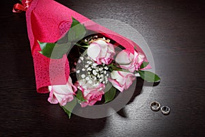 Bouquet of roses in a package of red paper and wedding rings