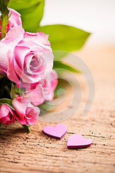 Bouquet of roses with two little hearts on a wooden background