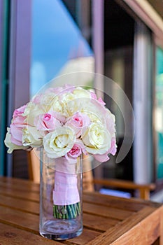 A bouquet of roses, in a vase, on the table, looking fresh and beautiful, with pink and yellow flowers.