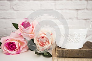 Bouquet of roses on a white desk, A large cup of coffee over old books, Romantic floral frame background, Floral Styled Wall Mock