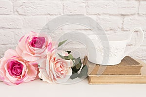 Bouquet of roses on a white desk, A large cup of coffee over old books, Romantic floral frame background, Floral Styled Wall Mock