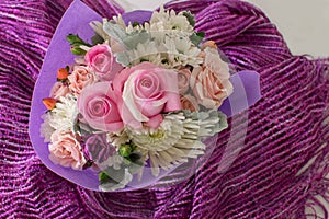 Bouquet of small roses and other mixed flowers on purple fabric.