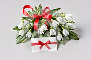 Bouquet of snowdrops tied with a red ribbon and a note attached to the bouquet. Martisor and Baba Marta